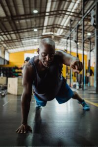 Muscular man demonstrating strength with a one-arm push-up in a gym.